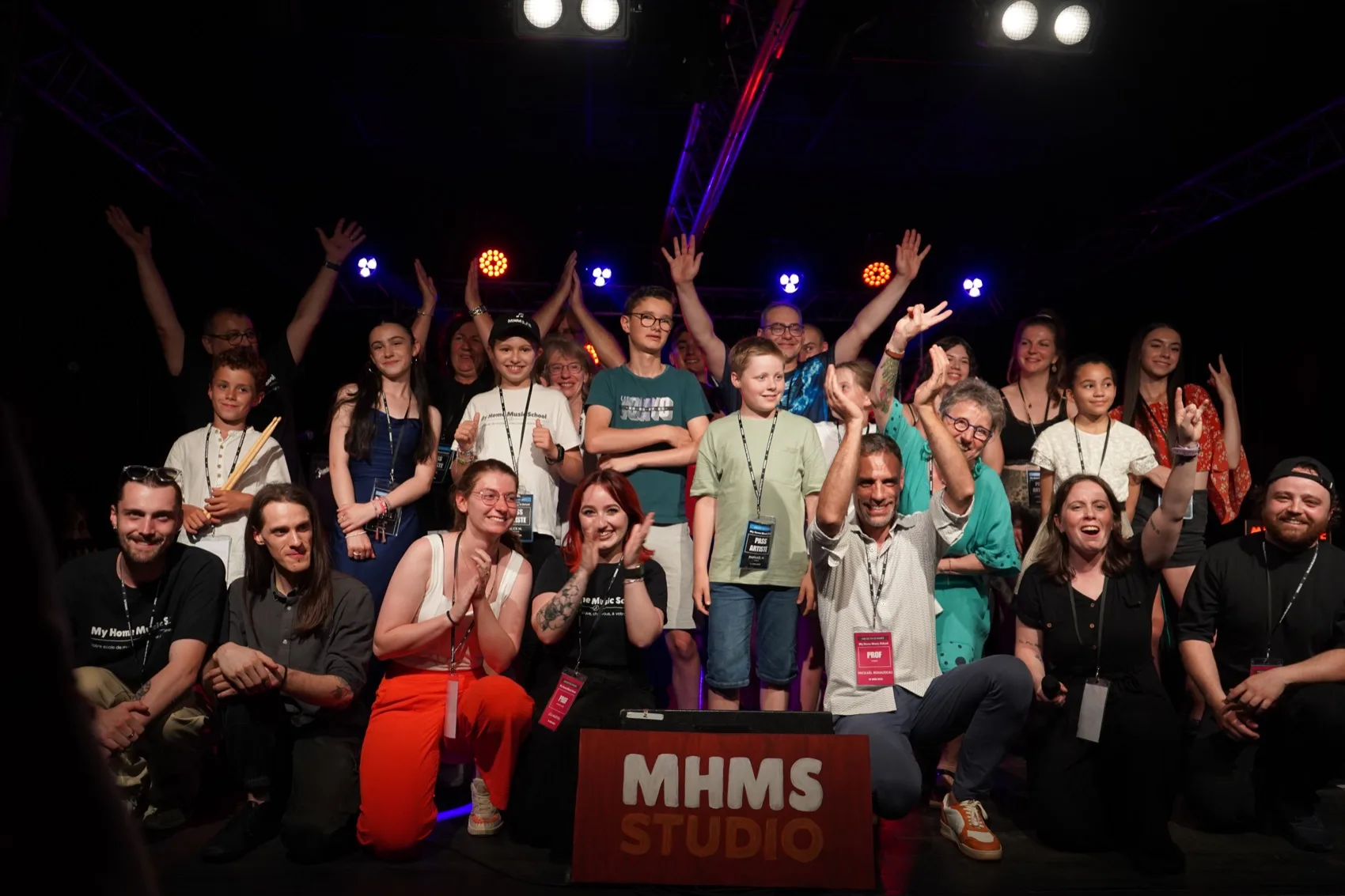 Concert de fin d'année de My Home Music School — élèves et professeurs réunis sur scène, bras levés