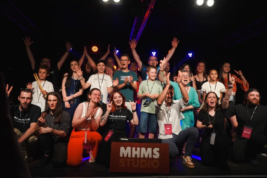 Élèves et professeurs, bras levés, sur la scène du Chaudron au concert des élèves 2025