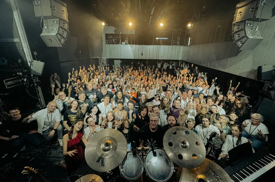 Élèves, professeurs et public réunis sur la scène et dans la salle de L'Empreinte à la fin du concert, bras levés